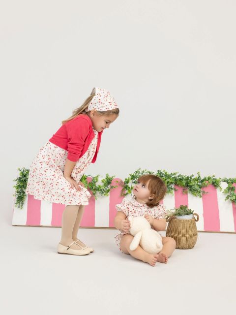 Two sisters playing on a pink-and-white striped studio set