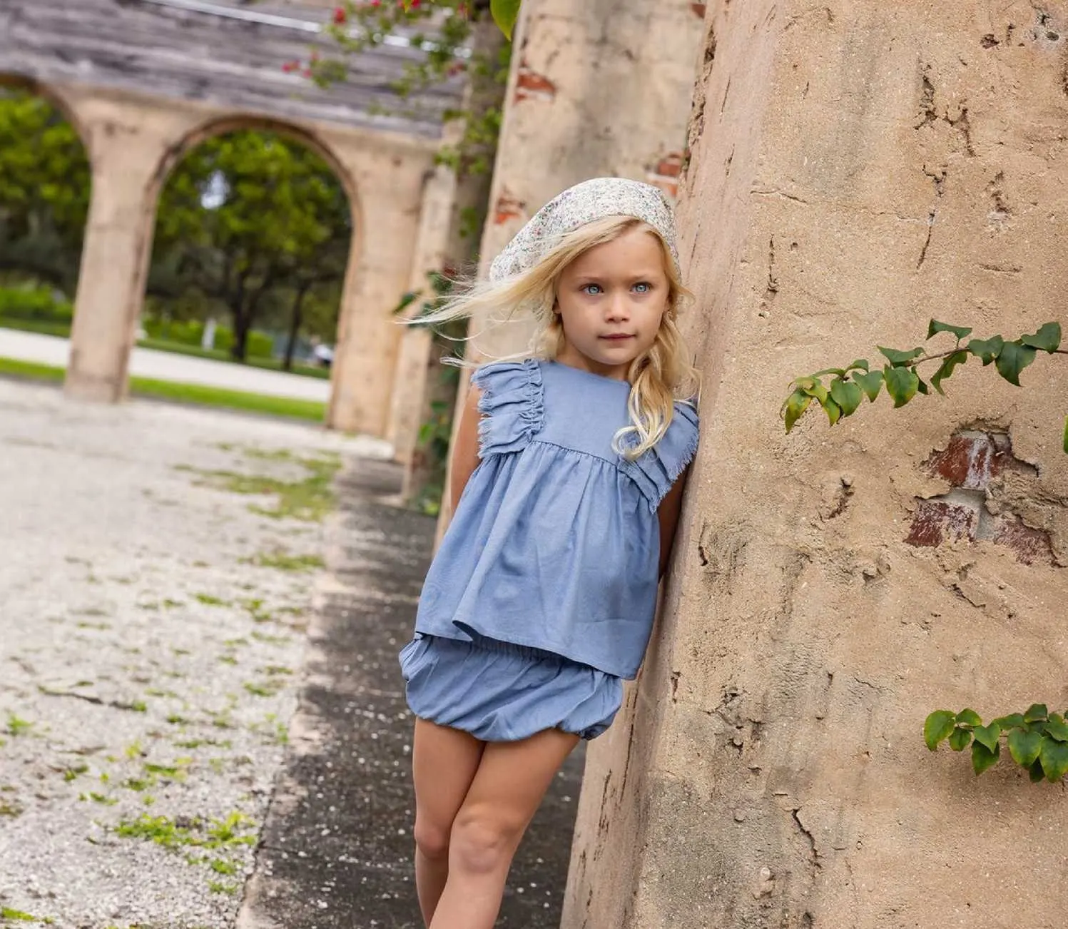 A little girl in blue beside a stone archway
